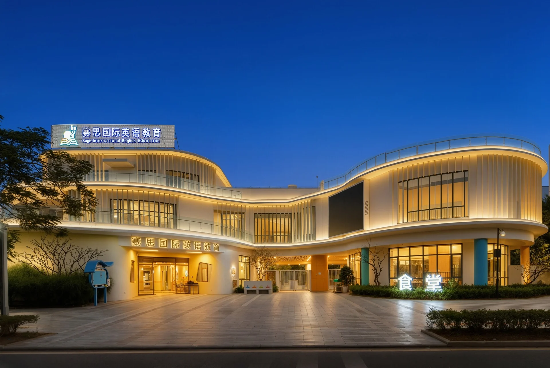 赛思国际英语教育巽寮湾校园外观,傍晚亮灯的教学楼与校门招牌